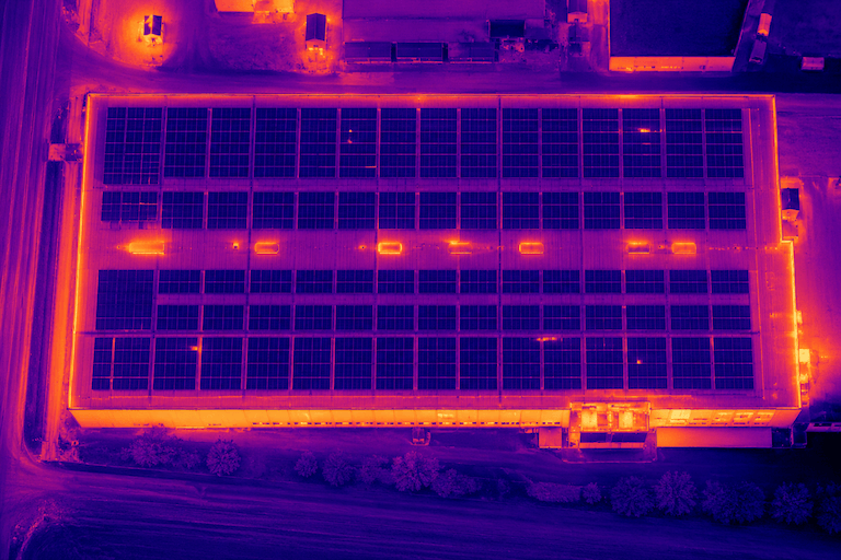Thermal inspection of a warehouse hall roof with PV panels - drone image in heat palette