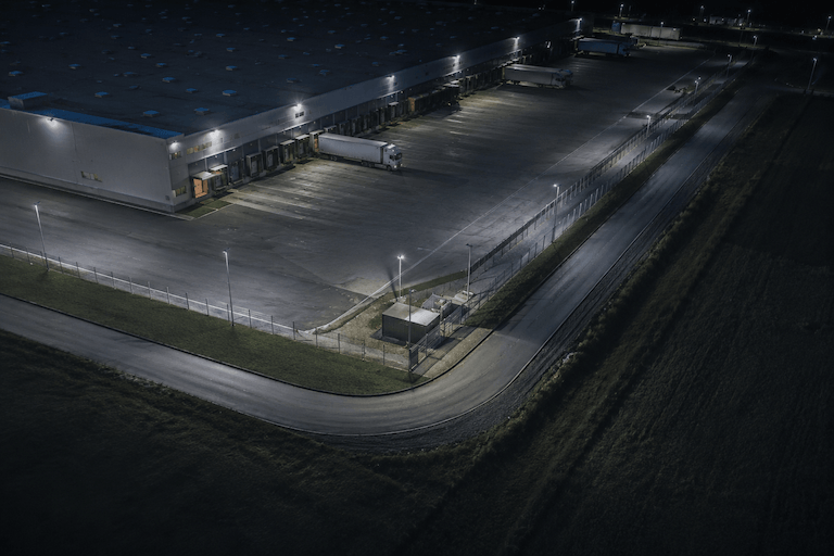 Night aerial view of a logistics centre - fenced site with illuminated yard